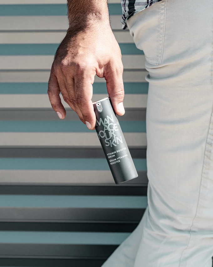 Mann hält das Vitamin Booster Serum in der Hand