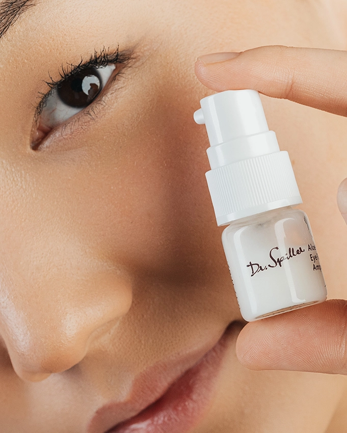 Woman holding a Dr. Spiller skin care product next to her face