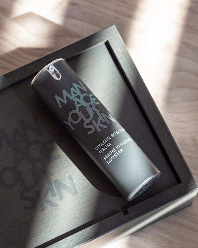 Vitamin Booster Serum Pumpspender liegt auf dekorativer Unterlage