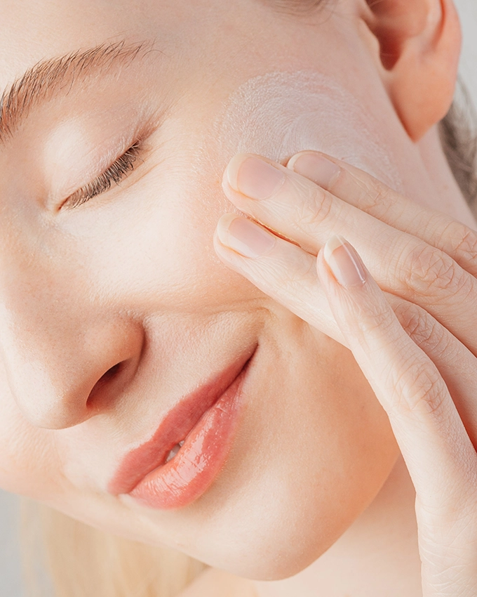 Frau peelt Gesicht mit Spezial Peeling Milch