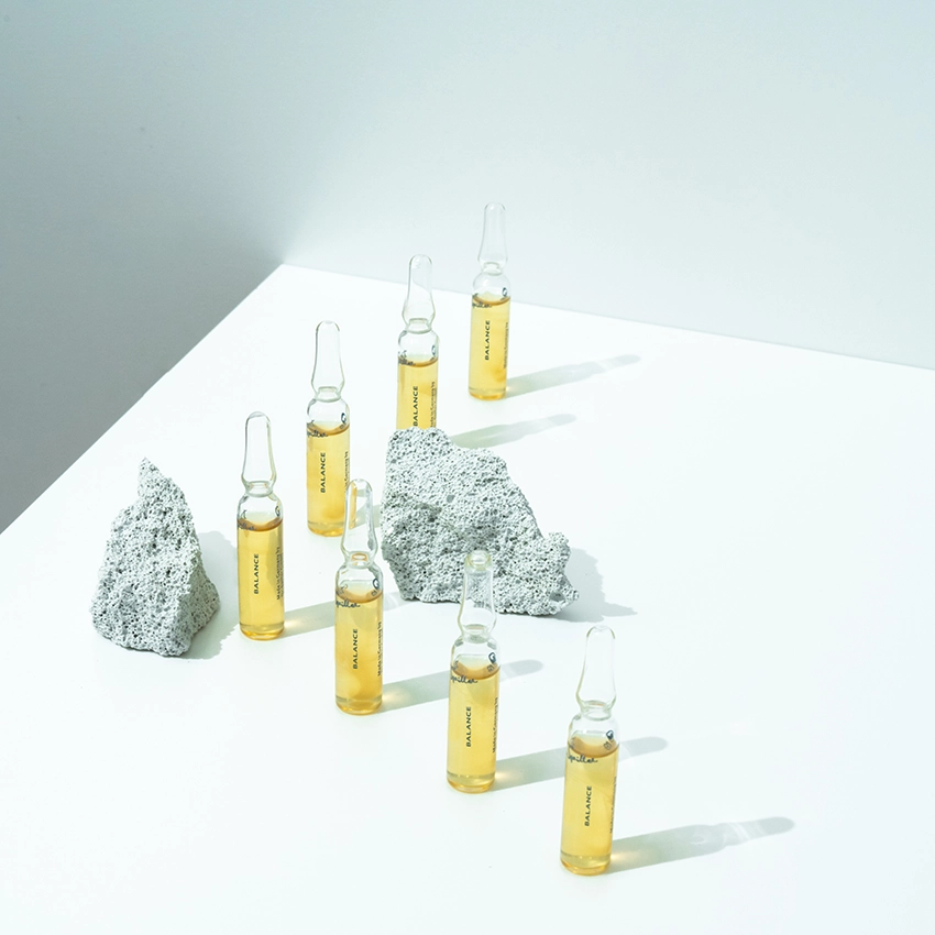 Several ampoules are placed on a table with decorative stones