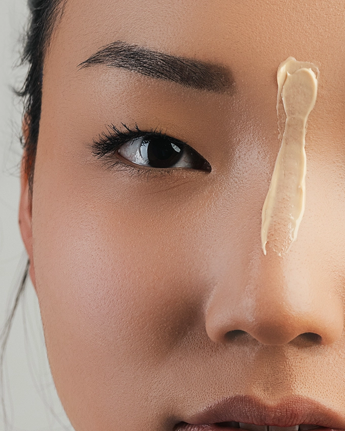 Auftragen einer beigefarbene Creme auf der Nase von vorne