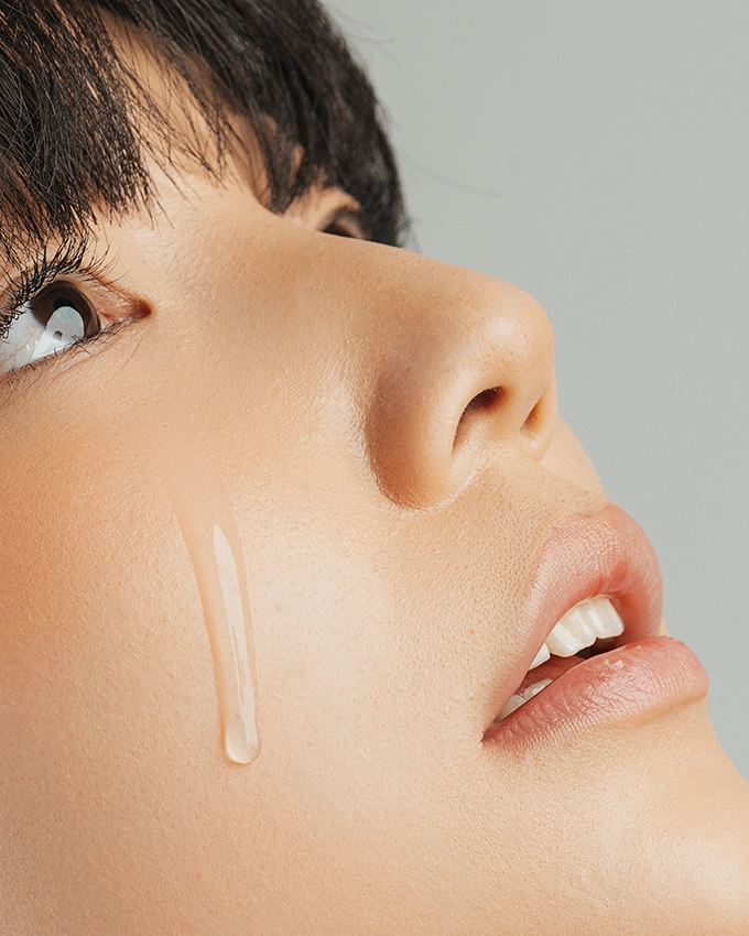Transparent serum is applied to a woman's cheek