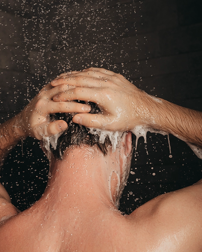 Mann wäscht sich mit dem Energizing Body & Hair Shampoo die Haare