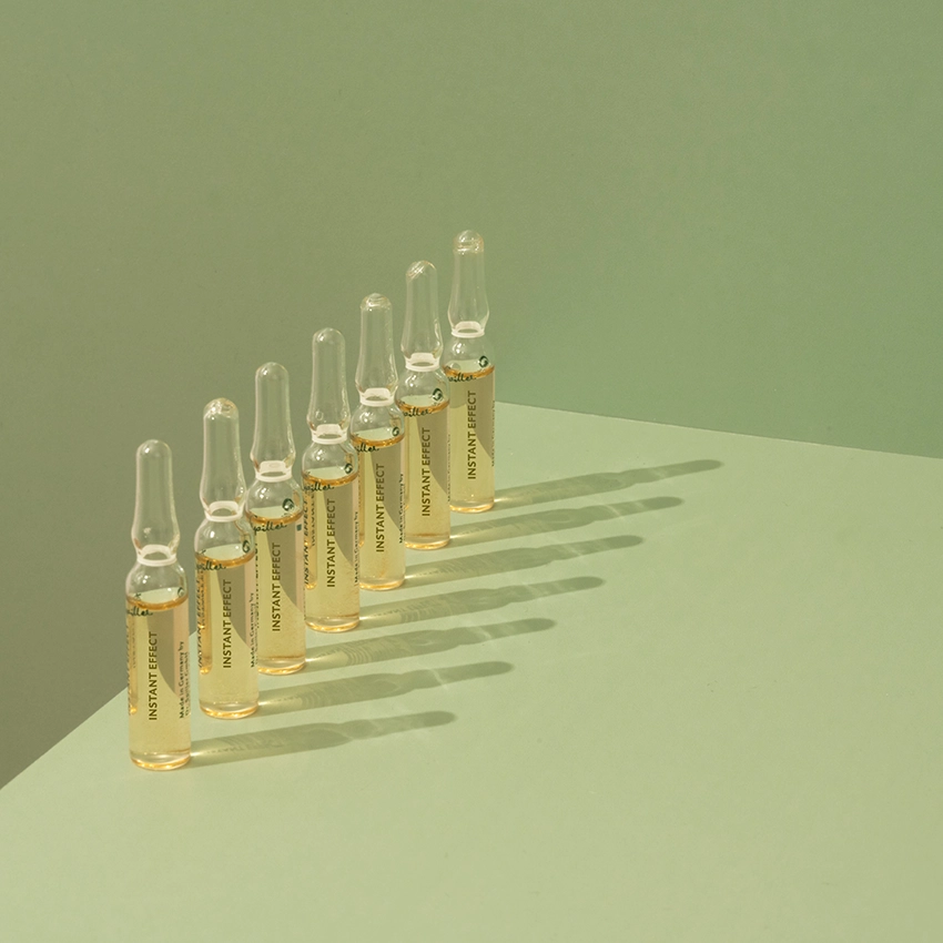 Several ampoules are placed on a table with a green background