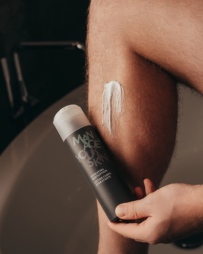 Mann cremt sich das Bein mit der Hydrating Bodylotion ein
