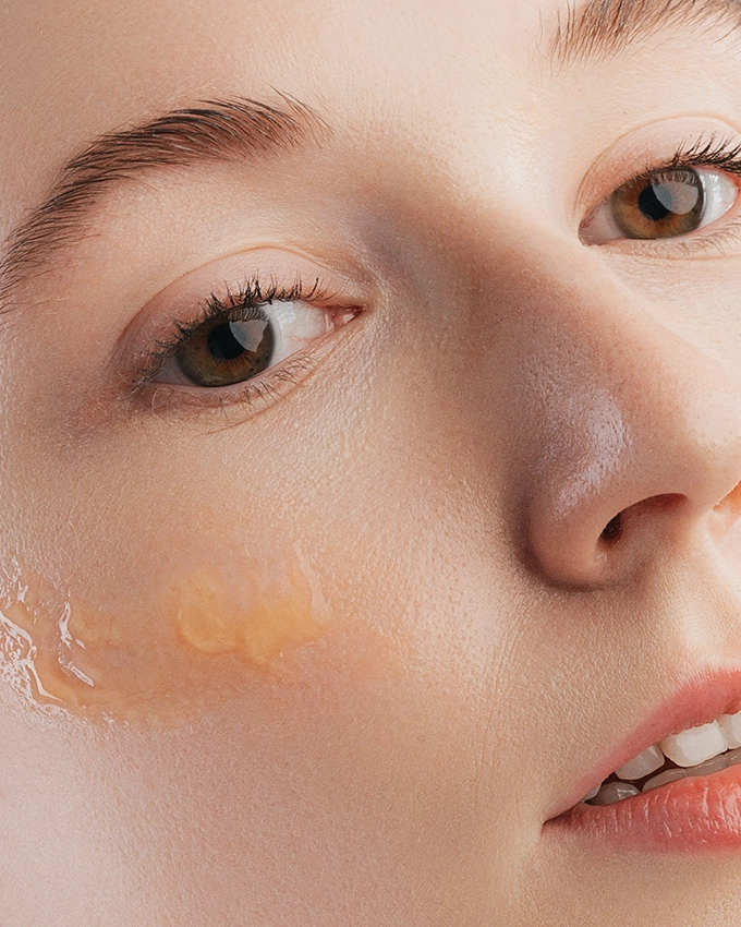 Serum is applied to a woman's cheek