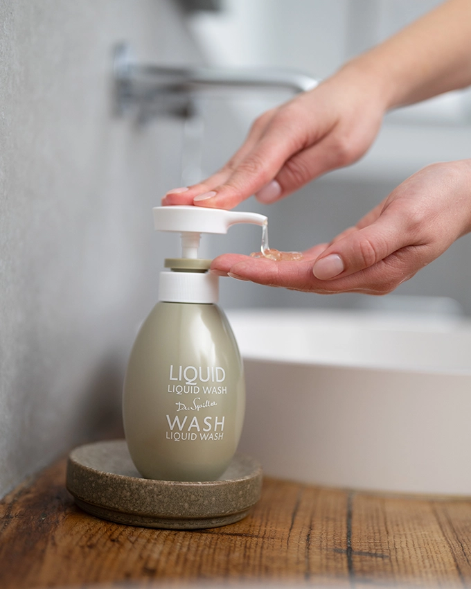 Weibliche Hände pumpen aus Liquid Wash Seife im Badezimmer